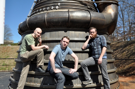 Leaning up against an F-1 engine. The same type that took man to the moon. The engine makes us look slightly cooler.